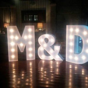 Letras gigantes 'M&D' de Animus Discotecas resplandecen en el suelo de madera, ofreciendo un fondo elegante y brillante para eventos y bodas.