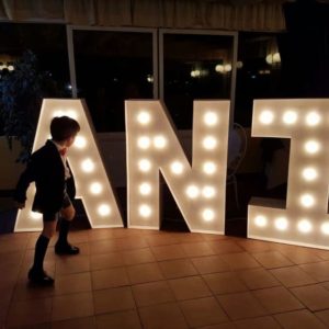 Un niño juega junto a las letras gigantes de Animus Discotecas en un evento nocturno, donde la iluminación aporta un ambiente festivo