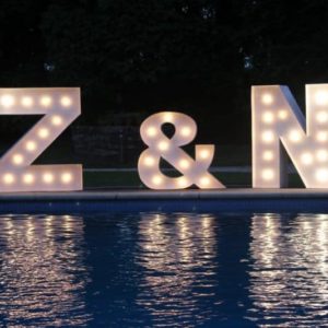 Letras gigantes 'Z&N' de Animus Discotecas se reflejan en la piscina, añadiendo un toque de magia a la noche en un exclusivo evento al aire libre