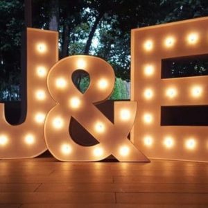 Letras gigantes 'J&E' de Animus Discotecas en un suelo de madera, creando un ambiente acogedor para eventos íntimos y celebraciones especiales.