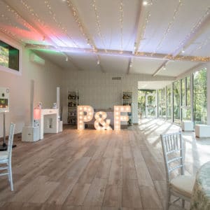Iluminación cálida de las letras gigantes 'P&F' en un salón de bodas acogedor, realzando la atmósfera para el evento.