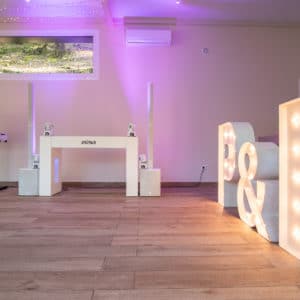 Letras gigantes iluminadas en madera, preparadas para celebrar momentos especiales en un espacio de eventos.