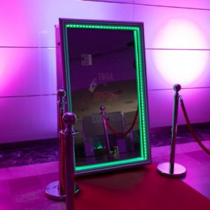Espejo fotomatón interactivo de Animus Discotecas Móviles con marco iluminado, acompañado de una selección de accesorios divertidos y señalizaciones creativas, listo para animar y personalizar eventos en A Coruña.